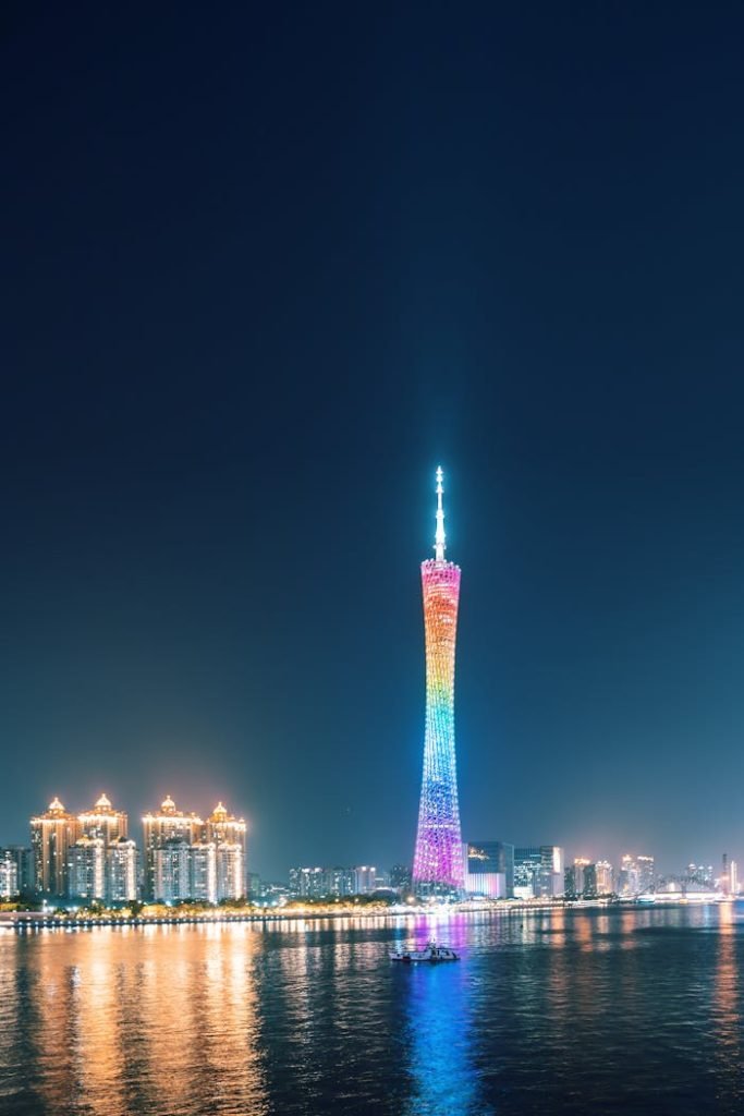 Stunning view of Canton Tower with vibrant rainbow lights reflecting on the Pearl River at night.