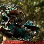 An ornate dragon statue on a red wall outdoors, showcasing intricate artistry.